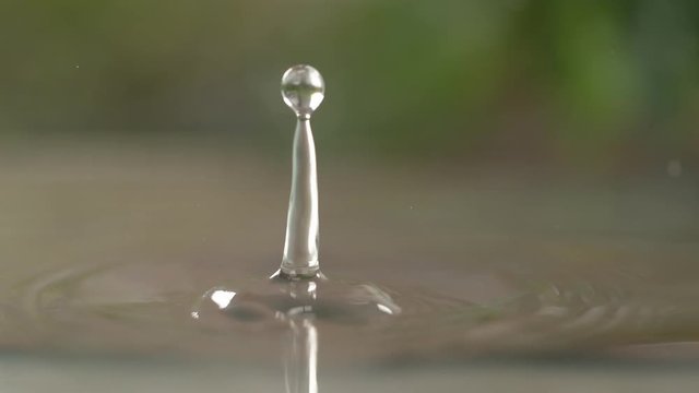 SLOW MOTION, MACRO, DOF: Tiny transparent droplets fall into a kitchen sink full of water. Cinematic shot of water droplets creating a beautiful ripple in the sink after someone leaves the tap open.