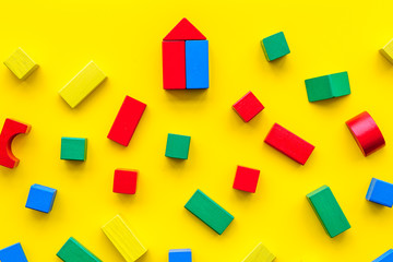 Children background. Wooden building blocks for developing and entertainment on yellow background top view