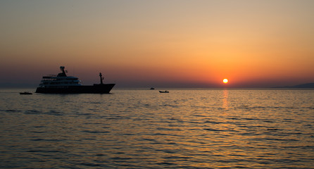 Sun setting over the sea with a yacht on the foreground