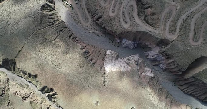 Top aerial scene discovering gravel road with serpentine shape at steep mountain slope. Iruya, Salta, Argentina 