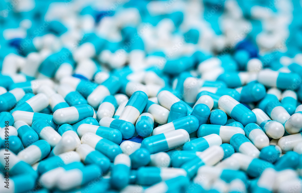 Wall mural Selective focus on pile of blue and white antibiotic capsule pill. Pharmaceutical production. Global healthcare. Antibiotics drug resistance. Antimicrobial capsule pills. Pharmaceutical industry.