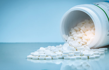 White tablets pill spilled out from white plastic bottle container. Pharmaceutical industry....