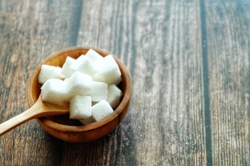Close up of sugar cube on wooden spoon.