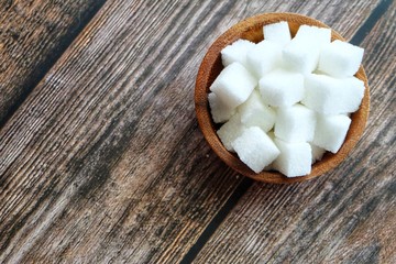Close up of sugar cube on wooden spoon.