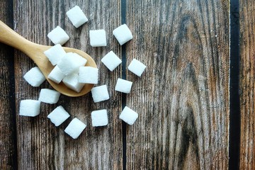 Close up of sugar cube on wooden spoon.