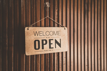 Open sign broad hanging on wood door front of cafe.