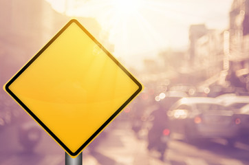 Empty yellow traffic sign on blur traffic road with colorful bokeh light abstract background.