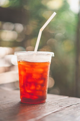 Ice coffee on wood table in cafe with green bokeh light abstract background.