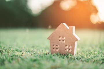 Copy space of home and life concept. Small model home on green grass with sunlight abstract background.