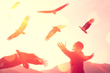 Man raise hand up on top of mountain and sunset sky with eagle birds fly abstract background.