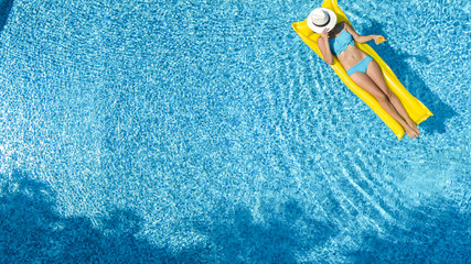Beautiful young girl relaxing in swimming pool, swims on inflatable mattress and has fun in water...