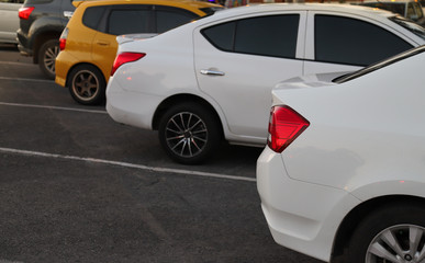 Plakat Closeup of back or rear side of white car and other cars parking in parking area in twilight evening. 