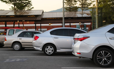 Closeup of back or rear side of bronze car and other cars parking in parking area with natural background in twilight evening. 