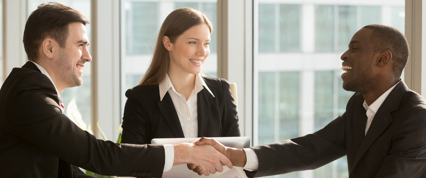 Horizontal image black and caucasian businesspeople greeting each other handshaking