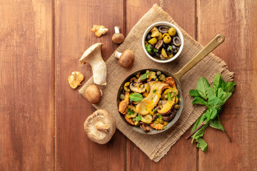 Fototapeta na wymiar A rustic mushrooms and olives saute in a cast iron pan with mint, shot from the top with a place for text
