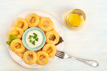 An overhead photo of squid rings with a glass of white wine, shot from the top with copy space