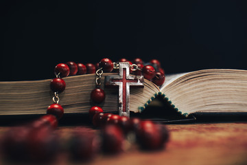 Old red Beads and crucifix on a Holy Bible background. Macro view.