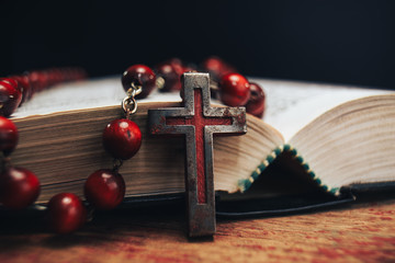 Old red Beads and crucifix on a Holy Bible background. Macro view.
