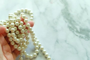  Close up of pearl necklace on woman hand and white background. 