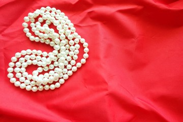 Close up of pearl necklace on red background. 