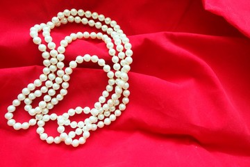 Close up of pearl necklace on red background. 
