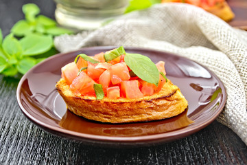 Bruschetta with tomato and basil in brown plate on board