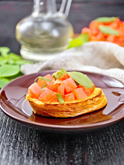 Bruschetta with tomato and basil in plate on dark board