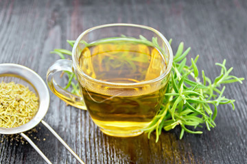 Tea of rosemary in cup with strainer on board