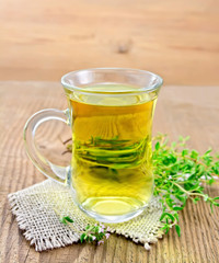 Tea of thyme in mug on wooden board