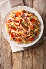 Italian pasta with baked shredded pork, cheese, tomato sauce and herbs close-up on a plate. Vertical top view