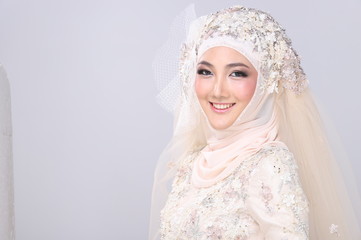 Asian Charming muslim arabic bride in Lace Bead Embroidery creammy yellow wedding dress and hijab headscarf, close-up on Fashion Make up Eyes Face, studio lighting grey background isolated.