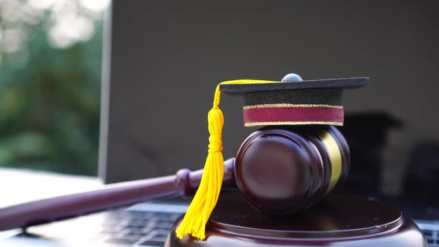 Graduation diploma hat / Judge gavel on computer notebook. Concept of graduate online study international abroad about jurisprudence laws certificate in university distance education for learning.