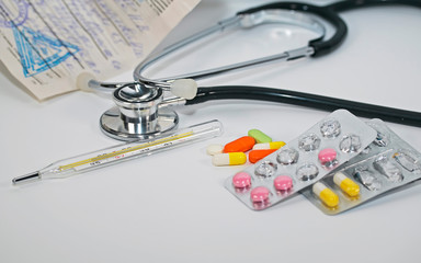  different drugs, vitamins, antibiotics and tablets lie on a white background with a prescription and thermometer