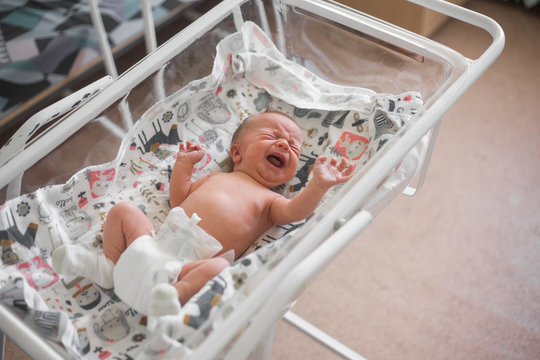 Newborn Baby Boy Right After Giving Birth In Hospital, View From Above, Baby In Crib Crying