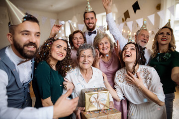 A portrait of multigeneration family with presents on a indoor birthday party.