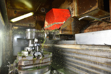 The process of drilling and grinding holes in the body of the valve on the CNC machine. Yellow-green coolant splashes into place