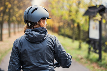 A rear view of active senior woman with bicycle helmet standing outdoors.