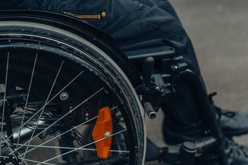 Fototapeta premium Close-up of male hand on wheel of wheelchair during walk in park