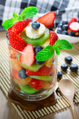 Diet-Fresh tasty mix fruit salad in the glass bowl decorated with mint leaves on the wooden table, healthy breakfast, weight loss concept.