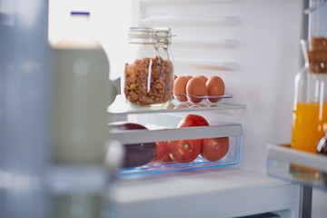 Fototapeta premium Opened fridge full of groceries. Selective focus on groceries.
