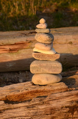 Pile of stones balancing on a wood log.