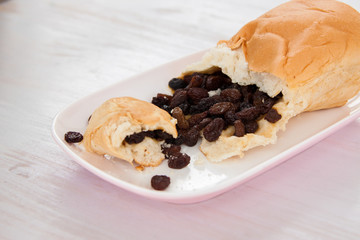 Raisins bread on the plate put on white color paint wood floor