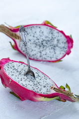 Two halves of dragon fruit with spoon on white background, tropical fruit