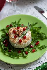 Healthy nutritious lunch or dinner for two: grilled camembert with grains of pomegranate, a branch of rosemary and nuts on a cushion of arugula. 
