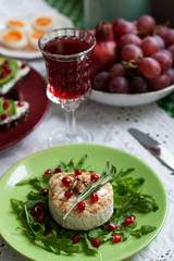 Healthy nutritious lunch or dinner for two: grilled camembert with grains of pomegranate, a branch of rosemary and nuts on a cushion of arugula. 