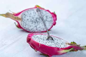 Two halves of dragon fruit with spoon on white background, tropical fruit