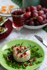 Healthy nutritious lunch or dinner for two: grilled camembert with grains of pomegranate, a branch of rosemary and nuts on a cushion of arugula. 