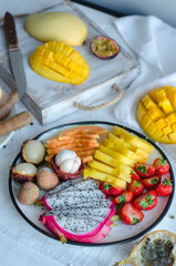 Many kinds of tropical fruits on white table. Mangosteen, lychee, tamarind, cherimoya, granadilla, mango, passion fruit, rambutan, strawberry, papaya.