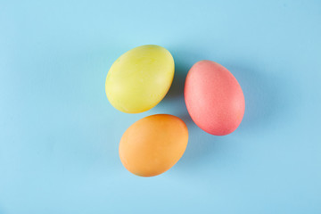 Bunch of blank painted Easter eggs of different pastel color on bright paper background with a lot of copy space for text. Top view, flat lay, close up.