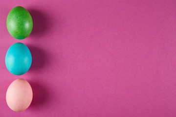 Bunch of blank painted Easter eggs of different pastel color on bright crimson paper background with a lot of copy space for text. Top view, flat lay, close up.